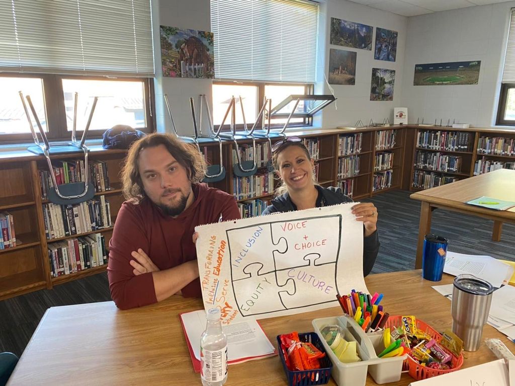Two teachers posing with a hand-drawn puzzle-piece image